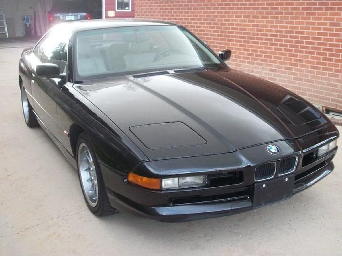Glossy black BMW 8 Series on driveway after professional detailing