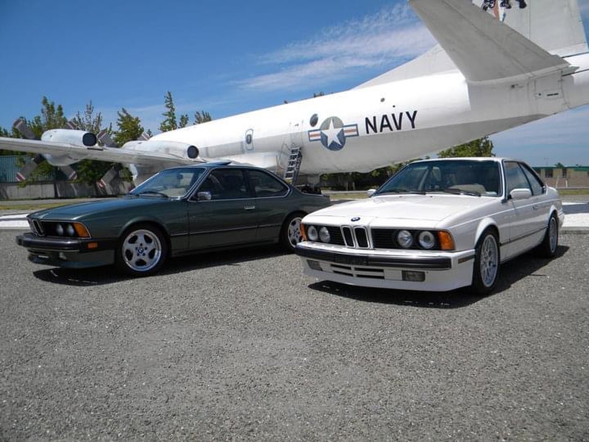 Pair of classic BMW coupes detailed for a show and Navy aircraft backdrop
